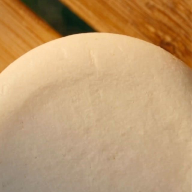 A shampoo bar resting on a wooden board, curing