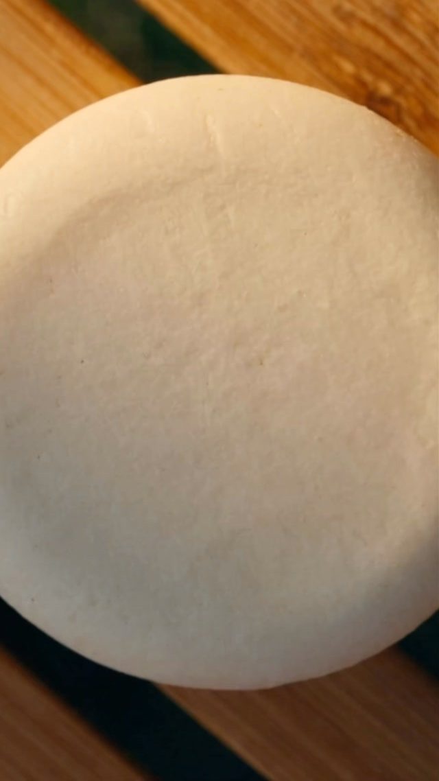 A shampoo bar resting on a wooden board, curing